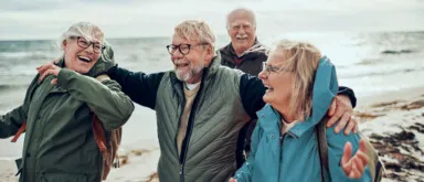 Two couples smiling together while walking on a beach near the ocean