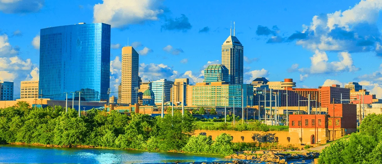 landscape view of downtown indianapolis showing buildings trees and a river