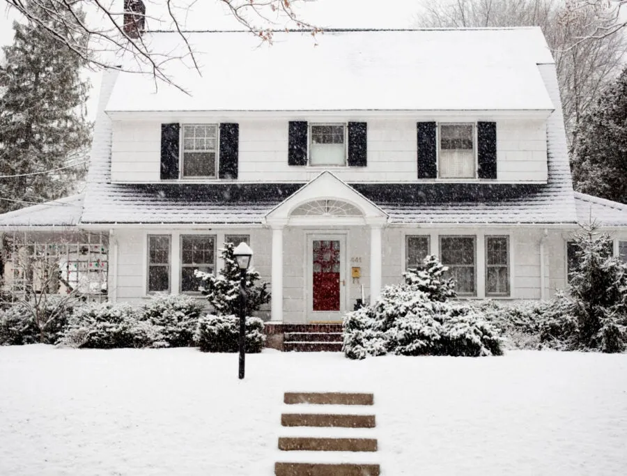 Exterior home winter snow on roof and lawn.