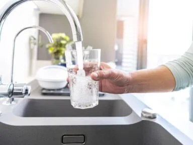 Close up woman hand filling a glass of water directly from the tap. Water contamination symptoms