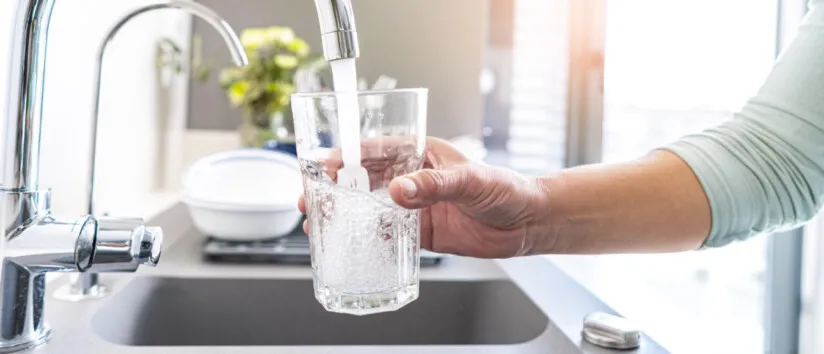 Close up woman hand filling a glass of water directly from the tap. Water contamination symptoms