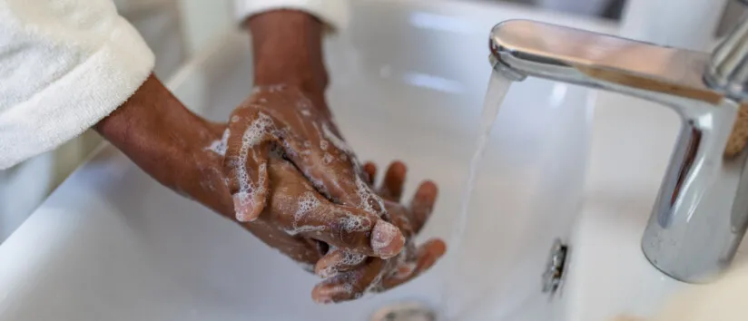 Close-up of a person lathering hands with soap and water over a bathroom sink, promoting soft water