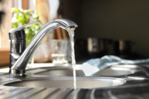 Water running from tap into kitchen sink. pros and cons of salt-free water softeners.