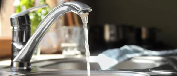 Water running from tap into kitchen sink. pros and cons of salt-free water softeners.