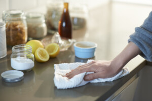 Woman cleaning a kitchen worktop with natural cleaning products lemon, bicarbonate of soda and vinegar to conserve water at home.