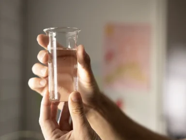 a person holding a beaker with a clear liquid