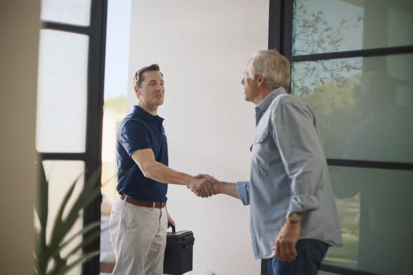 a leaf home sales person greeting a homeowner and shaking hands with another man