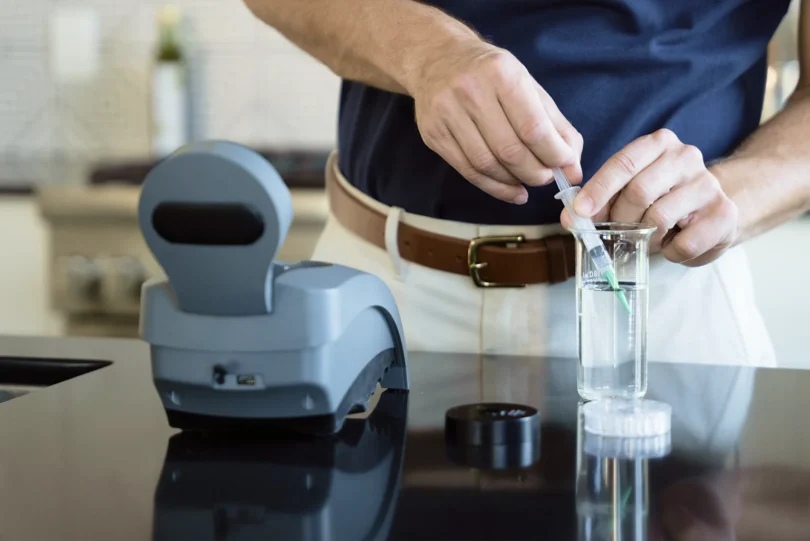 a person holding a syringe in a beaker testing water quality