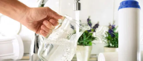 A jug of water filled by the tap next to a water filter